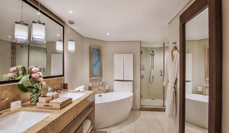 Junior Suite  Spa-style hotel bathroom with a large freestanding soaking tub, a double marble vanity, a glass walk-in shower, and a full-length mirror at Royal Palm Beachcomber Luxury by Kenwood Travel