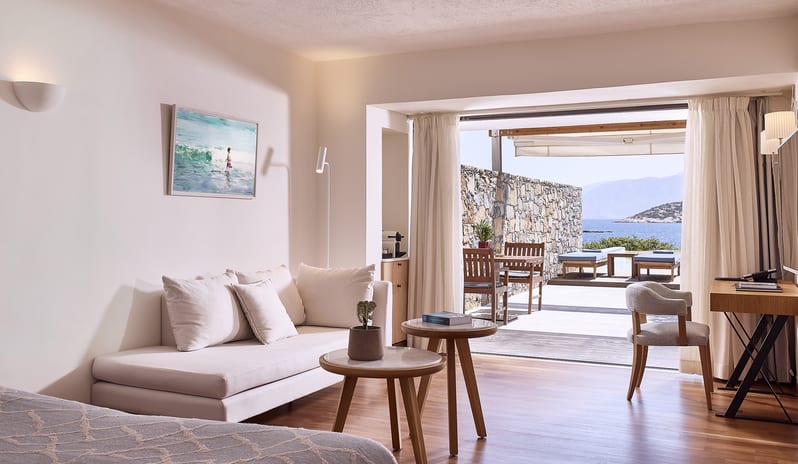 Classic Studio Private Pool Sea View cream sofa, marble-top coffee tables, and a private terrace with a stone wall, outdoor dining area, and a private pool overlooking the sea at St. Nicolas Bay Resort by Kenwood Travel