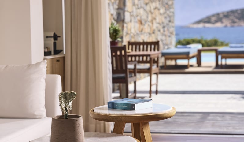 Classic Studio Private Pool Sea View cream sofa, marble-top coffee tables, and a private terrace with a stone wall, outdoor dining area, and a private pool overlooking the sea at St. Nicolas Bay Resort by Kenwood Travel
