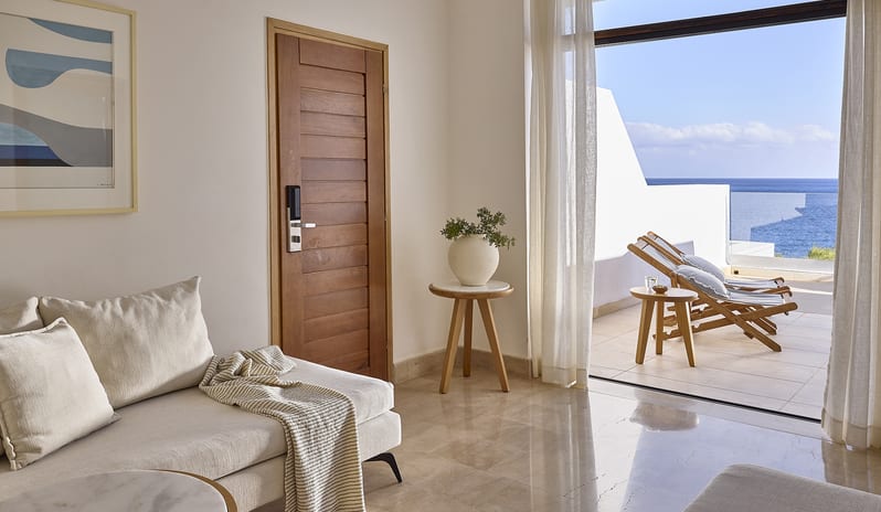 Classic Suite One Bedroom Sea View living room with a private terrace and sun loungers overlooking the sea at St. Nicolas Bay Resort by Kenwood Travel