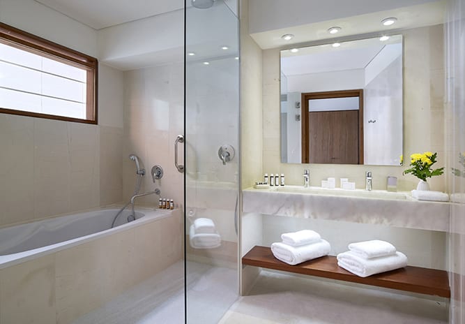 Classic Suite One Bedroom Sea View bathroom with marble vanity, walk-in shower, and soaking tub at St. Nicolas Bay Resort by Kenwood Travel