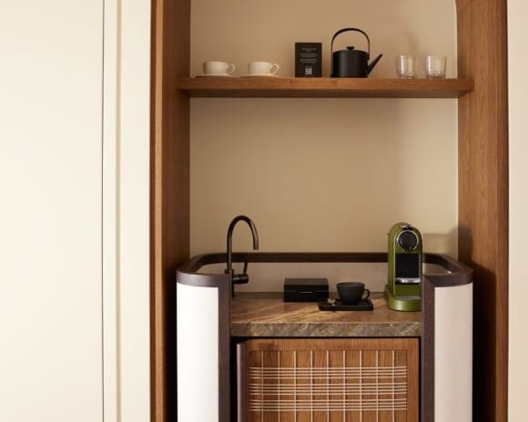 The Collection One bedroom Suite Sea View Private Pool minibar and coffee station featuring a marble countertop, an olive green espresso machine, and a custom wood cabinet within an arched alcove at Daios Cove by Kenwood Travel