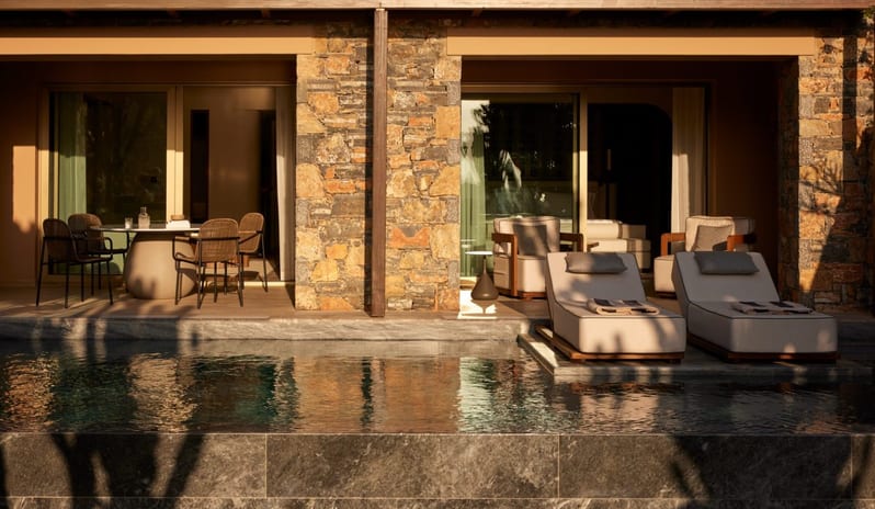 The Collection Two Bedroom Suite Sea View Private Pooll infinity pool surrounded by stone walls, sun loungers, and lush green cacti, overlooking a coastal landscape at Daios Cove by Kenwood Travel