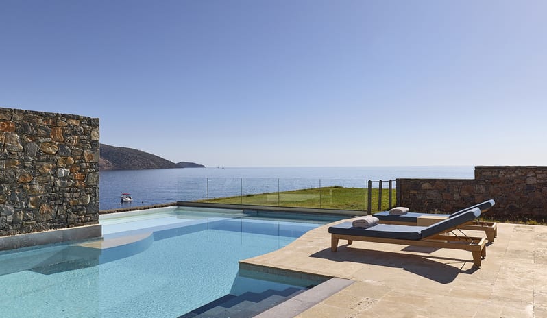 Club Suite One Bedroom Private Pool Sea View private infinity pool on a stone terrace with two wooden sun loungers facing the calm blue sea and distant hills at St.Nicolas Bay Resort by Kenwood Travel