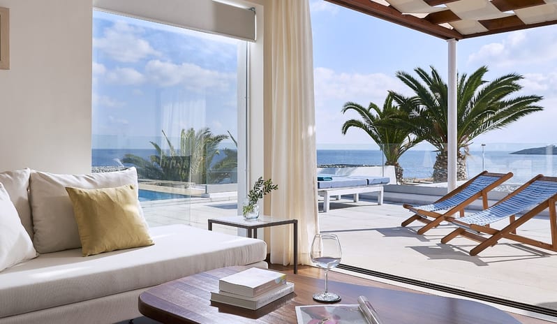 Club Suite One Bedroom Private Pool Sea View lounge with floor-to-ceiling windows, palm trees, and a private pool area overlooking the sea at St.Nicolas Bay Resort by Kenwood Travel