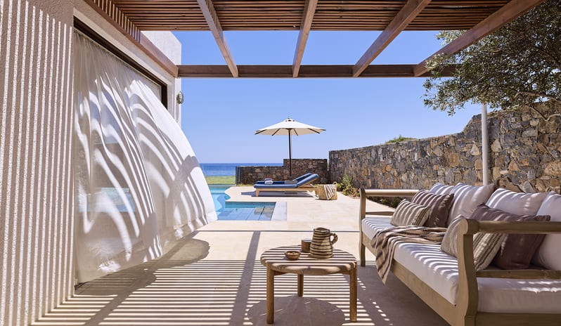 Club Suite One Bedroom Private Pool Sea View terrace with a wooden pergola, private infinity pool, stone wall, and comfortable outdoor sofa facing the ocean under a clear sky at St.Nicolas Bay Resort by Kenwood Travel