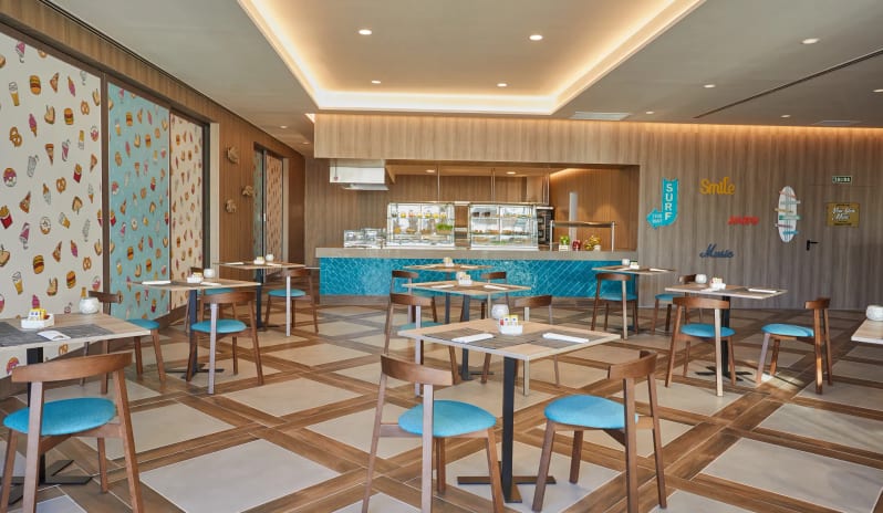 Barefoot Grill modern wooden dining tables with turquoise blue chairs and a vibrant food-themed wallpaper at Dreams Lanzarote Playa Dorada Resort & Spa by Kenwood Travel