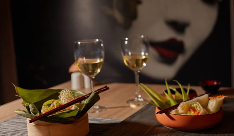Himitsu resh vegetable spring rolls in an orange bowl and a dish served in a bamboo steamer with banana leaves at Dreams Lanzarote Playa Dorada Resort & Spa by Kenwood Travel