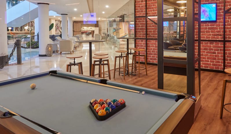Spin Music Lounge & Half Time Sports Bar Interior view of a modern lounge featuring exposed brick walls, industrial metal framing, warm wood flooring, and circular pendant lighting at Dreams Lanzarote Playa Dorada Resort & Spa by Kenwood Travel