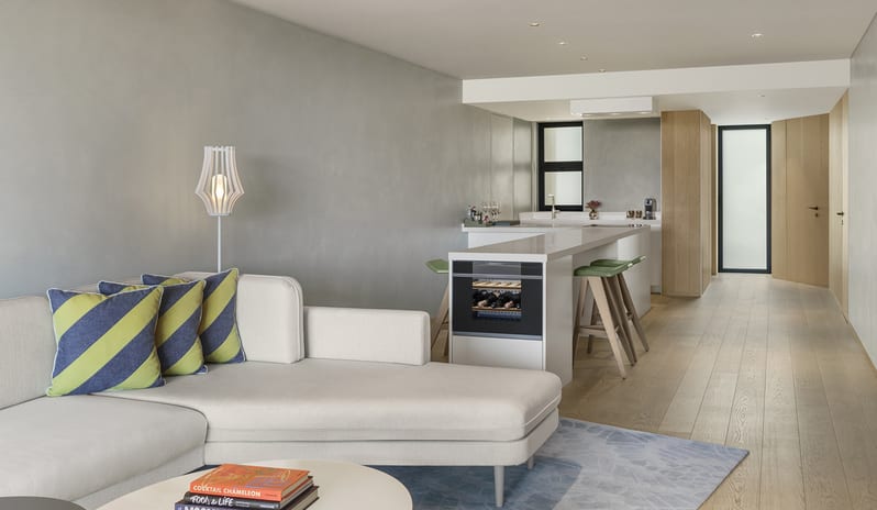 Superior Two Bedroom Suite featuring a white sectional sofa, breakfast bar with green stools, and wine cooler at W Algarve by Kenwood Travel