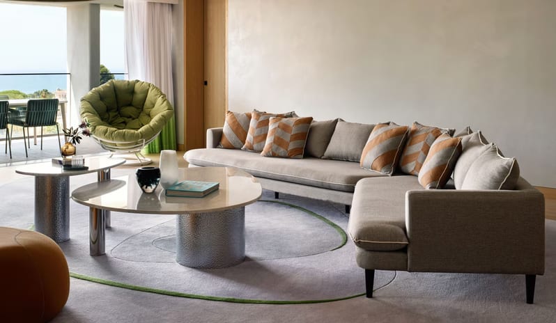 Supreme Three-Bedroom Residence Contemporary luxury lounge with a curved grey area rug, minimalist decor, and large glass doors opening to a scenic sea view terrace at W Algarve by Kenwood Travel