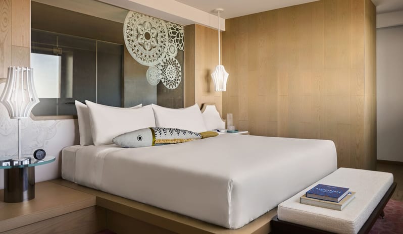 Penthouse I, Two Bedroom Suite with Pool bedroom featuring a white plush bed with a decorative fish-shaped pillow, a wooden end-of-bed bench, and blue Portuguese-style tile accents at W Algarve by Kenwood Travel