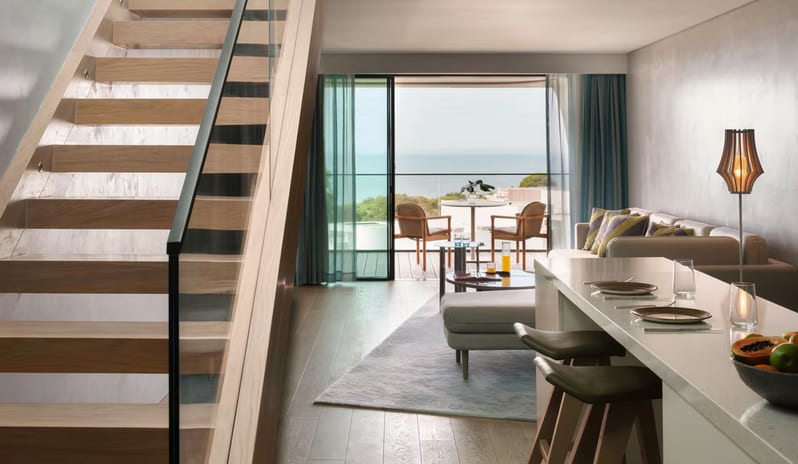Supreme Two Bedroom Penthouse with Pool featuring a modern wooden staircase with glass railings, an open-concept living and dining area, and a private balcony with an ocean view at W Algarve by Kenwood Travel
