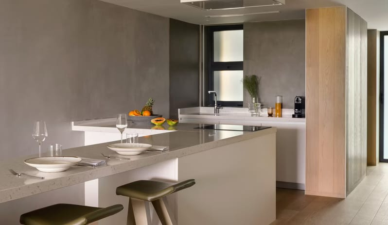 Supreme Two Bedroom Penthouse with Pool kitchen featuring a sleek white quartz island with an integrated breakfast bar, olive green leather stools, and gray industrial-style walls at W Algarve by Kenwood Travel