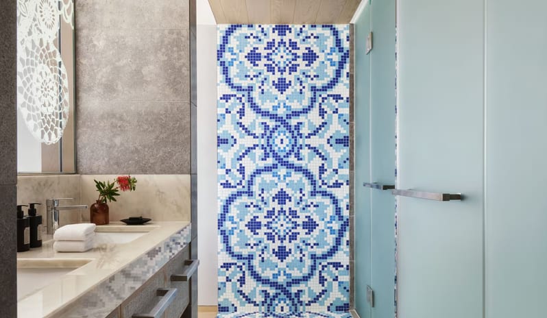 Penthouse I, Two Bedroom Suite with Pool Private bathroom featuring a vibrant blue and white Portuguese-style mosaic tile wall, a marble vanity with a recessed sink, and frosted glass shower doors at W Algarve by Kenwood Travel