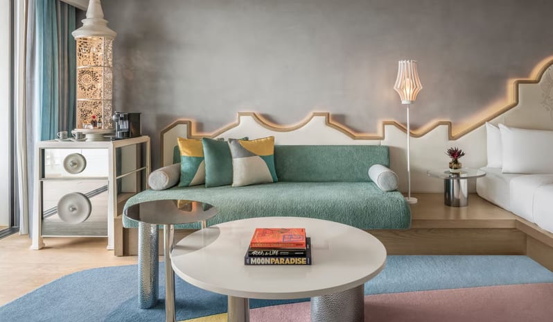 Premier Private Garden Room lounge area featuring a teal daybed with geometric cushions, a white round coffee table with books, and a unique mirrored mini-bar cabinet with a decorative white lantern at W Algarve by Kenwood Travel