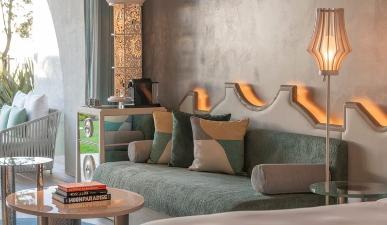 Superior Room living area featuring a sage green sofa with geometric cushions, a unique scalloped wall panel with ambient backlighting, and a modern floor lamp at W Algarve by Kenwood Travel