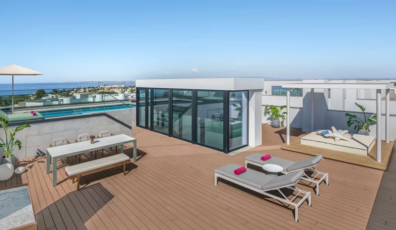 Supreme Two Bedroom Penthouse with Pool rooftop terrace with wooden decking, featuring a private infinity pool, a modern glass-enclosed staircase, outdoor dining furniture, and lounge chairs overlooking the ocean at W Algarve by Kenwood Travel