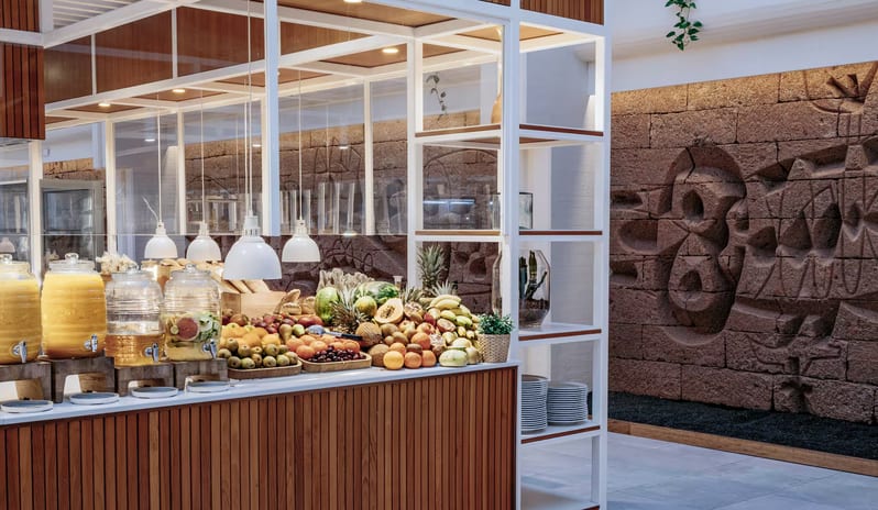 Malva Food Bazaar Restaurant dining room featuring a large carved stone relief mural, modern blue rope chairs, and set dinner tables with wine glasses at Paradisus Salinas Lanzarote by Kenwood Travel