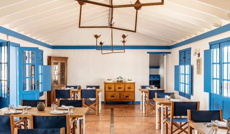 La Graciosa Restaurant Traditional indoor dining room at La Graciosa in Lanzarote featuring white walls with blue trim, wooden furniture, navy chairs, and high vaulted ceilings at Paradisus Salinas Lanzarote by Kenwood Travel