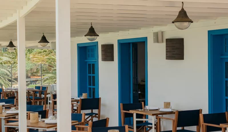 La Graciosa Restaurant Traditional blue-trimmed doorways, wooden tables with navy director chairs, and hanging pendant lights under a white pergola at Paradisus Salinas Lanzarote by Kenwood Travel