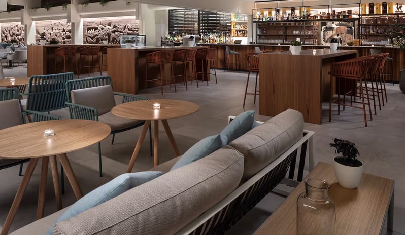 Ginger Lobby Bar lounge featuring wooden high-top tables with leather stools, teal wicker chairs at Paradisus Salinas Lanzarote by Kenwood Travel