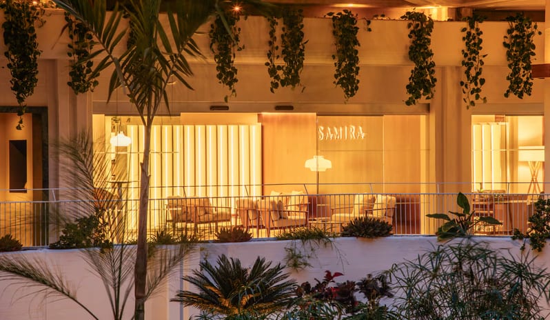 Samira restaurant featuring warm ambient lighting, vertical light panels, and a lush green terrace with hanging plants at Paradisus Salinas Lanzarote by Kenwood Travel