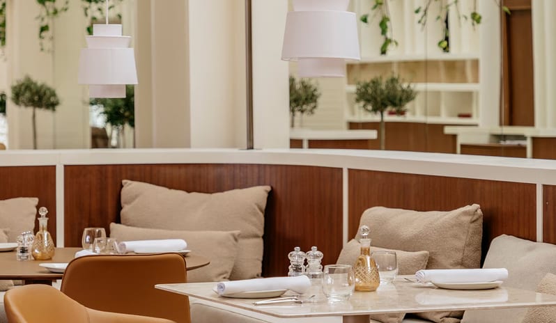 Samira restaurant dining setup featuring a curved wood-paneled banquette with plush beige cushions, a white marble tabletop at Paradisus Salinas Lanzarote by Kenwood Travel