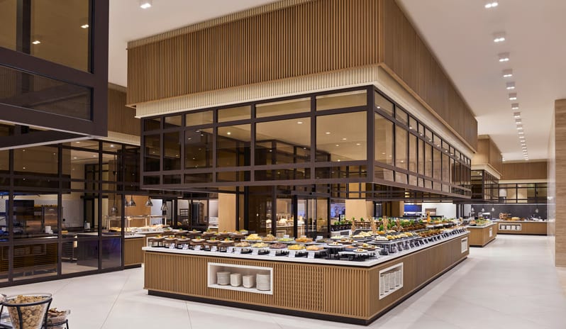 Zestful Bazaar Main Restaurant gourmet appetizers and cold salads displayed on a modern white marble buffet counter with light wood accents in a bright, upscale restaurant at Anda Barut Collection by Kenwood Travel