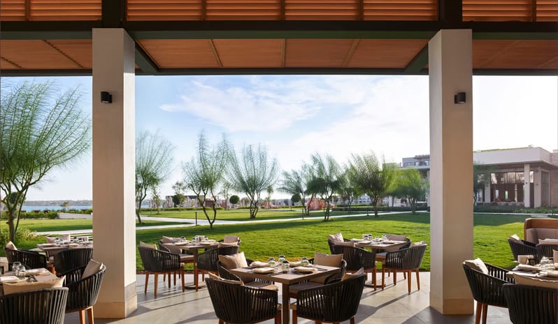 Tiger Restaurant patio with stylish wicker seating, wooden slat ceiling details, and a wide-angle view of a professionally landscaped resort gardenat Anda Barut Collection by Kenwood Travel