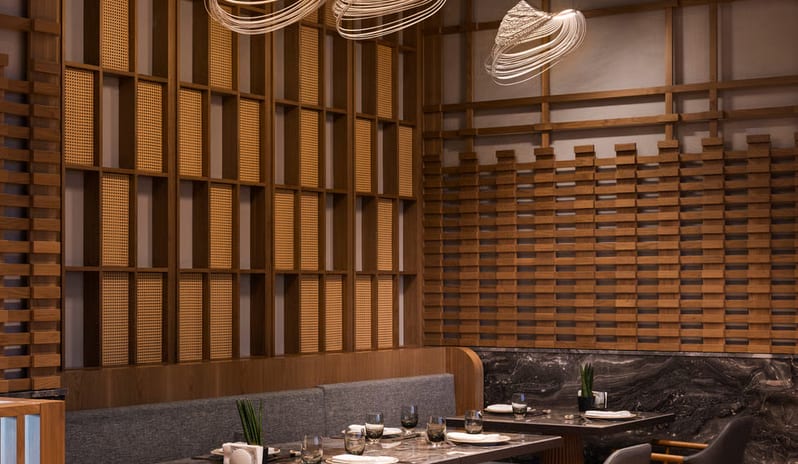 Tiger Restaurant interior showing intimate booth seating, designer lighting, and Japanese-inspired wooden wall craftsmanship at Anda Barut Collection by Kenwood Travel