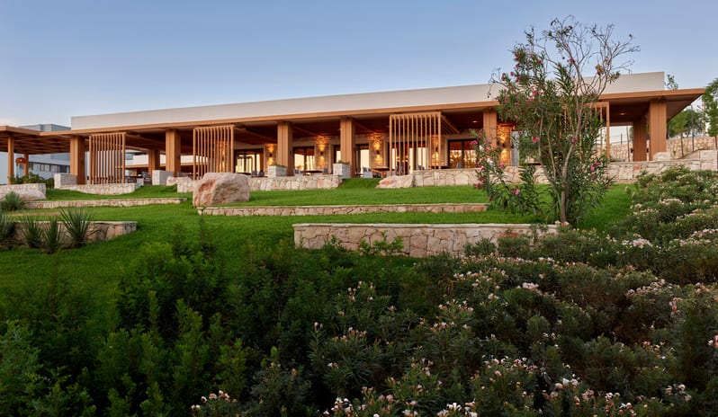 Mansion Restaurant International Kitchen featuring stone walls, wooden pergolas, and lush green terraced gardens under a clear blue sky at Anda Barut Collection by Kenwood Travel