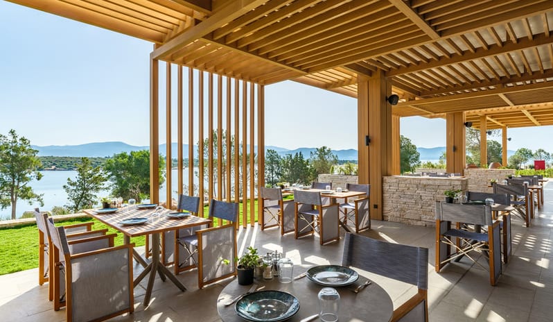 Mansion Restaurant International Kitchen dining area at a luxury Mediterranean resort featuring wooden sunshades and a panoramic view of the ocean and distant mountains at Anda Barut Collection by Kenwood Travel
