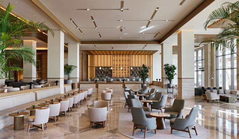 Soa Playhouse Ease Lobby Lounge Bar & Terrace lobby lounge featuring plush seating areas, marble flooring, and a sophisticated gold-accented bar in the background at Anda Barut Collection by Kenwood Travel