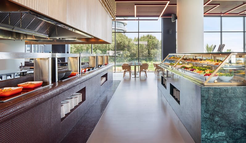 Degusto Adult Restaurant fresh salads and hot dishes displayed in a sleek glass and tile station with a bright, airy background at Voyage Belek Golf & Spa by Kenwood Travel