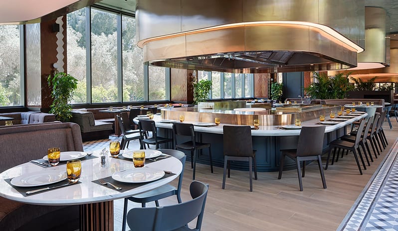 Kebappa Turkish Restaurant circular booth seating, modern pendant lighting, and large windows overlooking lush greenery at Voyage Belek Golf & Spa by Kenwood Travel
