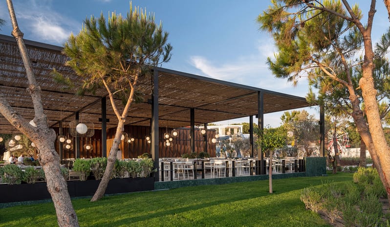 Vista Italian Restaurant featuring glowing globe pendant lights, a textured canopy roof, and evening ambient lighting at Voyage Belek Golf & Spa by Kenwood Travel