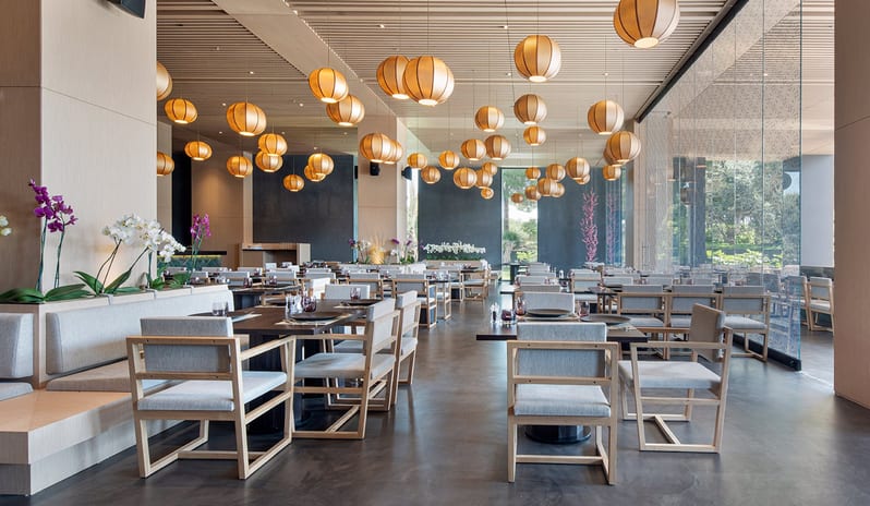 Wen Chinese Restaurant modern wooden seating, orchid floral arrangements, and numerous hanging spherical paper lanterns at Voyage Belek Golf & Spa by Kenwood Travel