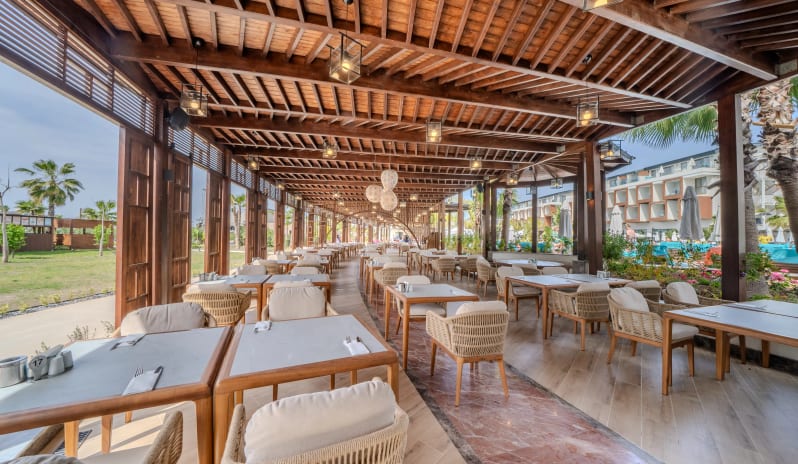 Liberty Fabay Balbura Snack Restaurant outdoor dining area at Liberty Fabay Balbura Snack Restaurant featuring wooden pergola, woven chairs, and pool view-Kenwood Travel
