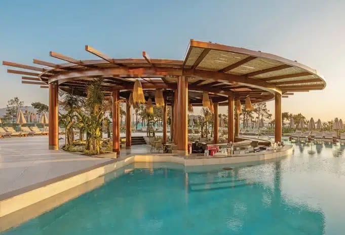 Adult Pool Bar poolside bar featuring a round wooden canopy structure, integrated seating in the water, and tropical landscaping at sunset at Liberty Signa Hotel by Kenwood Travel