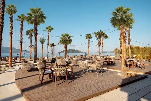Sunset Bar Outdoor beachfront lounge area at Liberty Signa Sunset Bar featuring wooden decking, palm trees, and modern wicker seating overlooking the ocean at Liberty Signa Hotel by Kenwood Travel