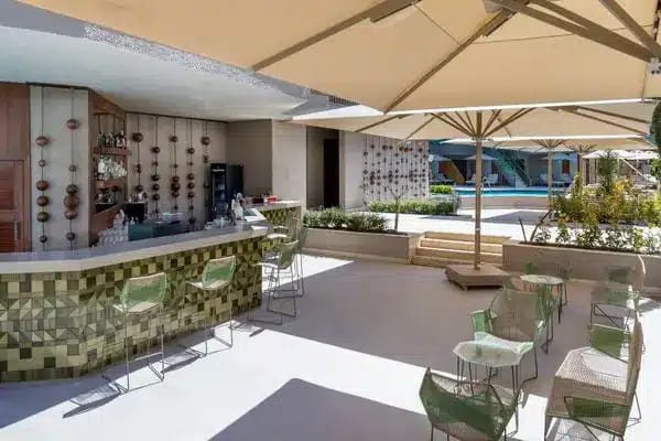 Oasis Bar a geometric tiled bar, green mesh seating, and large sun umbrellas by the pool at Liberty Signa Hotel by Kenwood Travel
