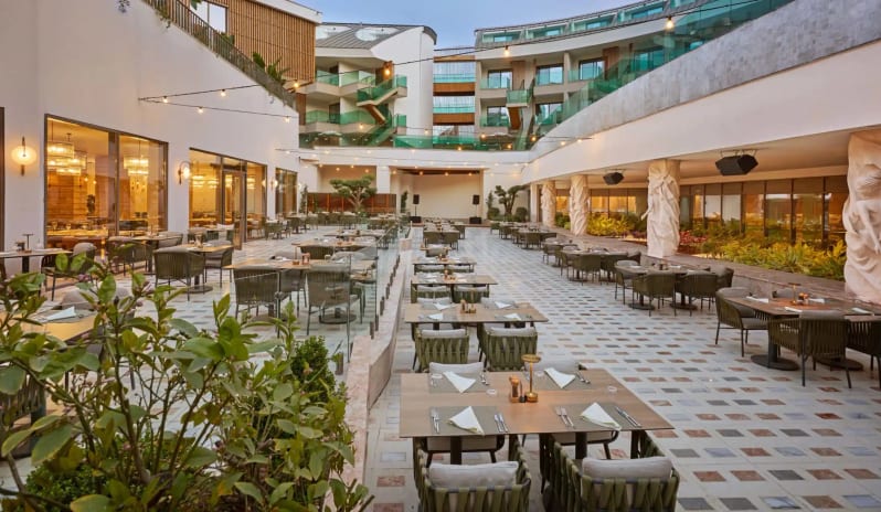 Ricotta A’la Carte Restaurant modern patio seating, string lighting, and luxury architecture under a twilight sky at Liberty Signa Hotel by Kenwood Travel