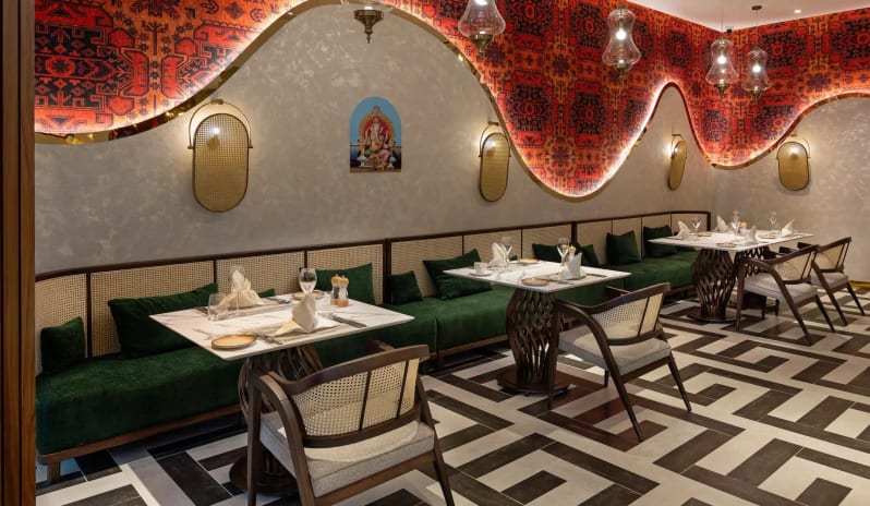 Puri A’la Carte Restaurant green velvet banquette seating, marble tables, and ornate red wall tapestries with Ganesha artwork at Liberty Signa Hotel by Kenwood Travel