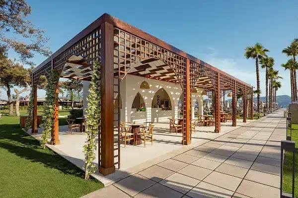 Waffle House wooden pergola at the Liberty Signa Waffle House outdoor restaurant with arched latticework and palm trees at Liberty Signa Hotel by Kenwood Travel