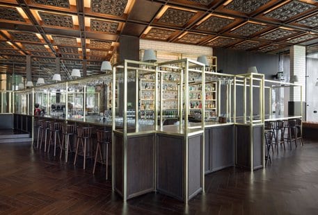 Barroom Bar brass frame structure, dark wood herringbone floors, and an ornate coffered ceiling with warm backlighting at Voyage Belek Golf & Spa by Kenwood Travel