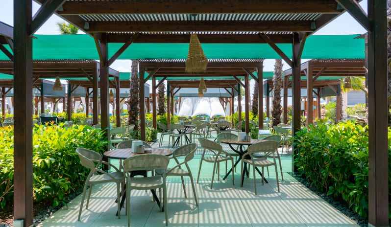 Patara Beach Snack Bar A sun-drenched outdoor seating area at a tropical resort featuring several wooden pergolas with slatted roofs at Liberty Fabay by Kenwood Travel
