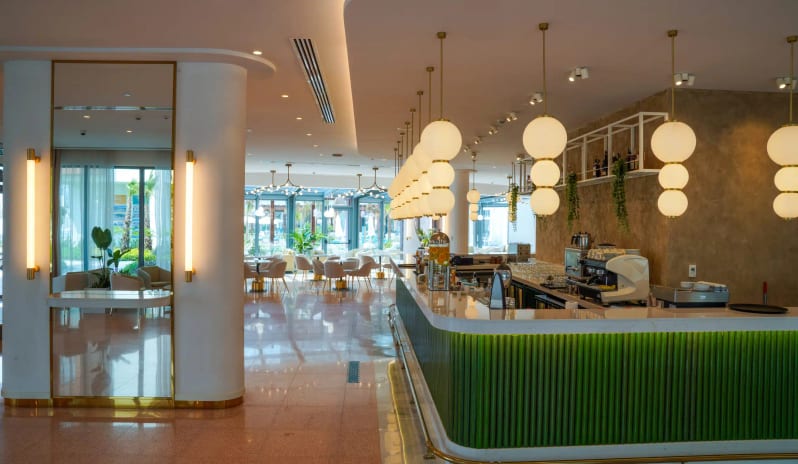 Apollon Bar green fluted bar counter, elegant globe pendant lighting, and polished terrazzo flooring at Liberty Fabay by Kenwood Travel