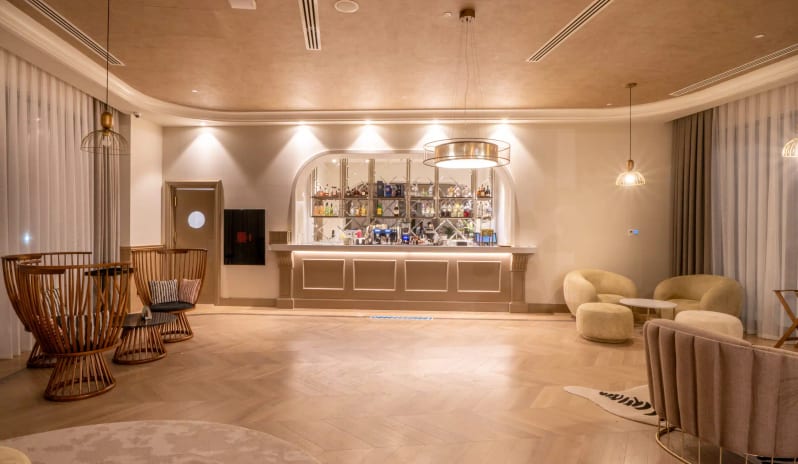 Gagai Lobby Bar herringbone wood floors, arched back-bar shelving, and contemporary gold pendant lighting at Liberty Fabay by Kenwood Travel