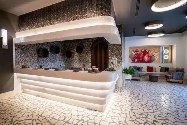 Spa Bar a sleek white illuminated counter, mosaic tile backsplash, and contemporary lounge seating at Liberty Fabay by Kenwood Travel